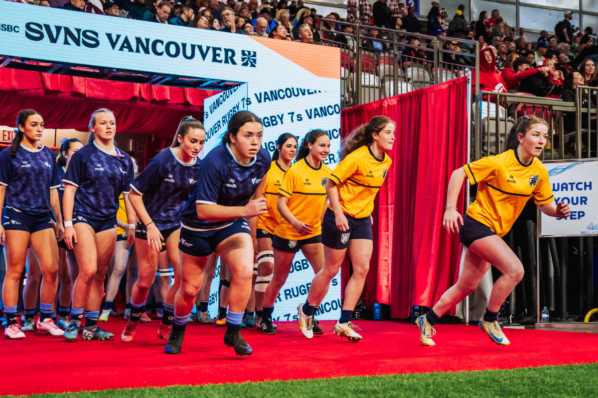 Rugby players sprint onto the field at SVNS Vancouver, with blue and yellow uniforms on a red carpet entrance
