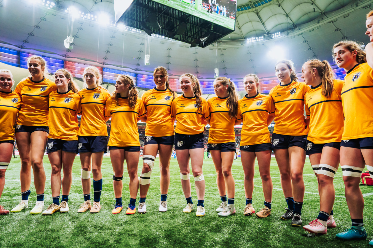 Rugby team in orange jerseys standing together on a stadium field before a match
