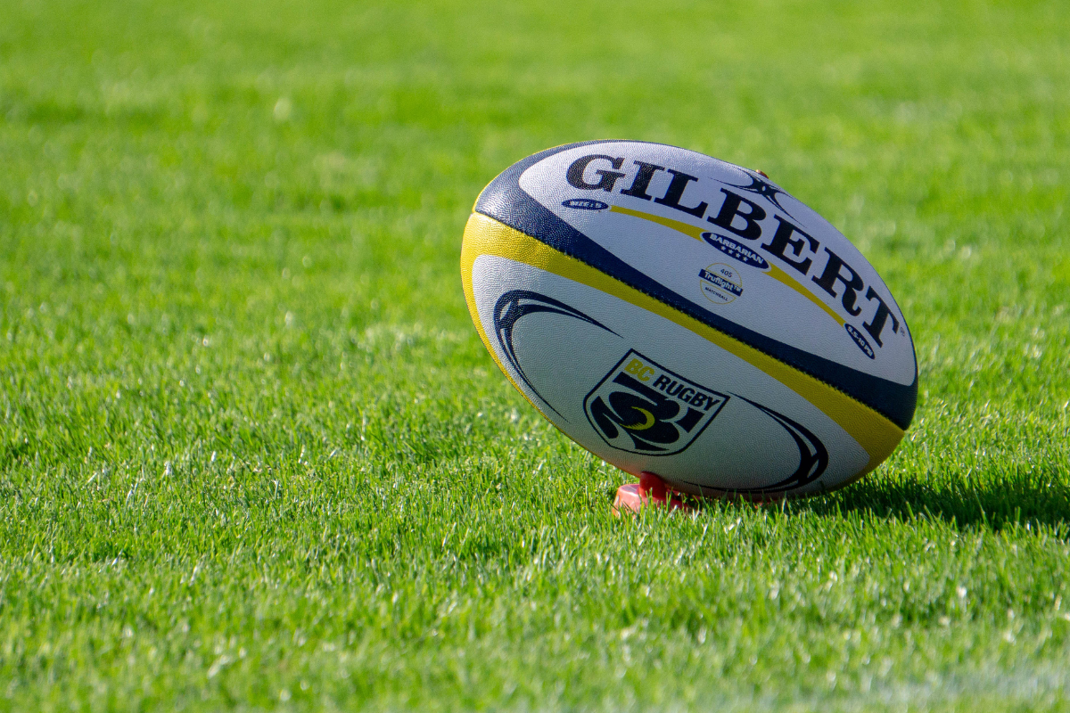 Rugby ball on green grass, tilted on a small tee in a field