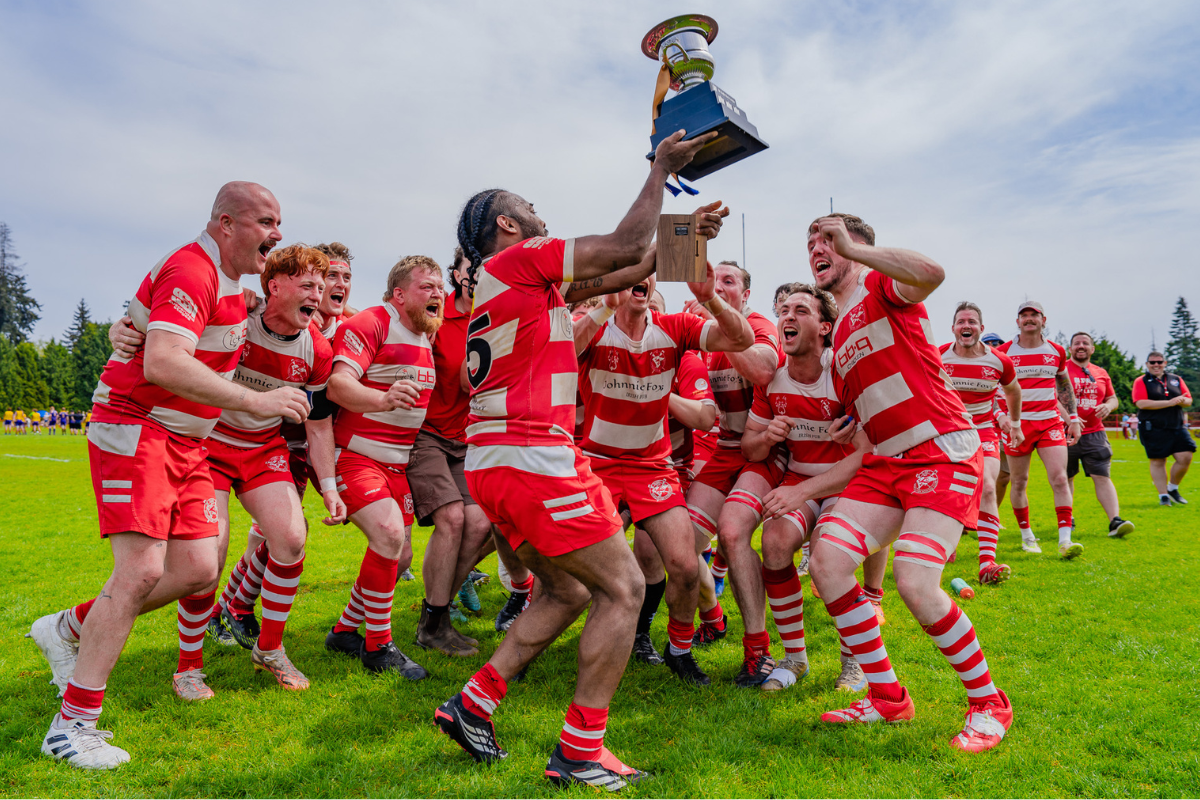 Soccer players in red and white uniforms celebrate on a field after a match
