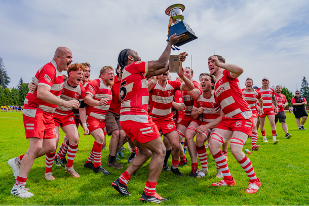Rugby players in navy-and-red uniforms embrace and smile after a match