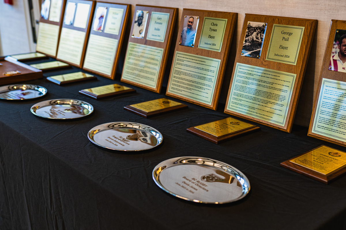 Award display table with framed certificates, gold plaques, and engraved plates on a black cloth cover