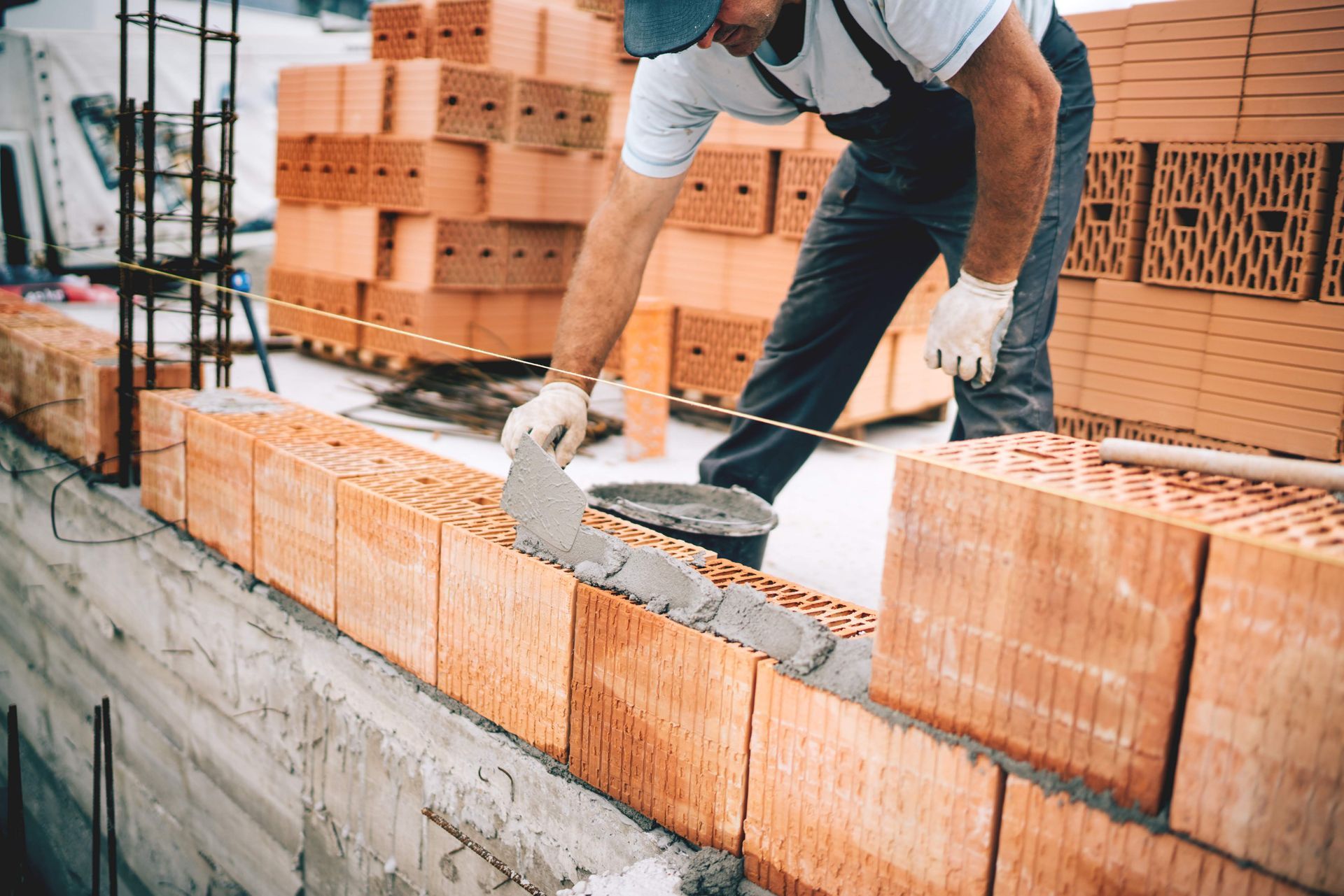 A construction worker is laying bricks on a wall.