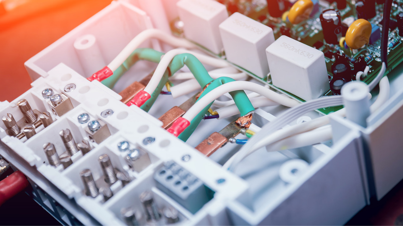 Close-up of a white circuit board with wires, connectors, and electronic components arranged in a tray
