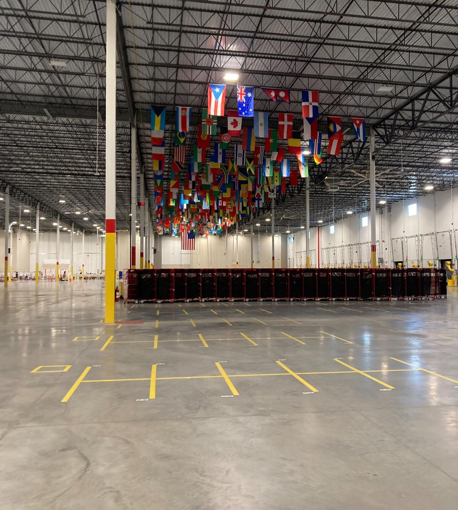 Empty warehouse interior with rows of hanging international flags over a marked concrete floor