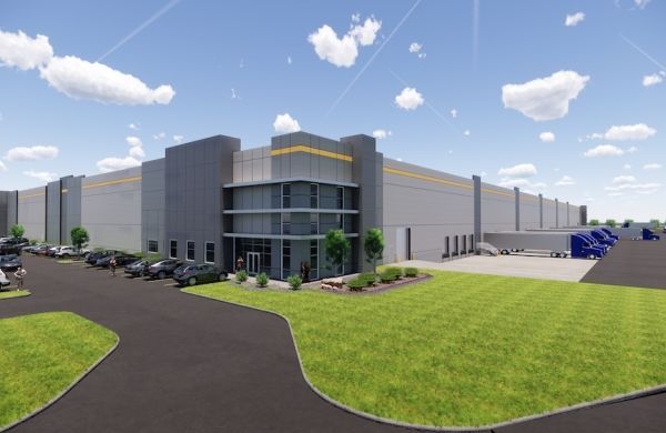 Large gray warehouse with landscaped entrance, black driveway, and blue sky with clouds