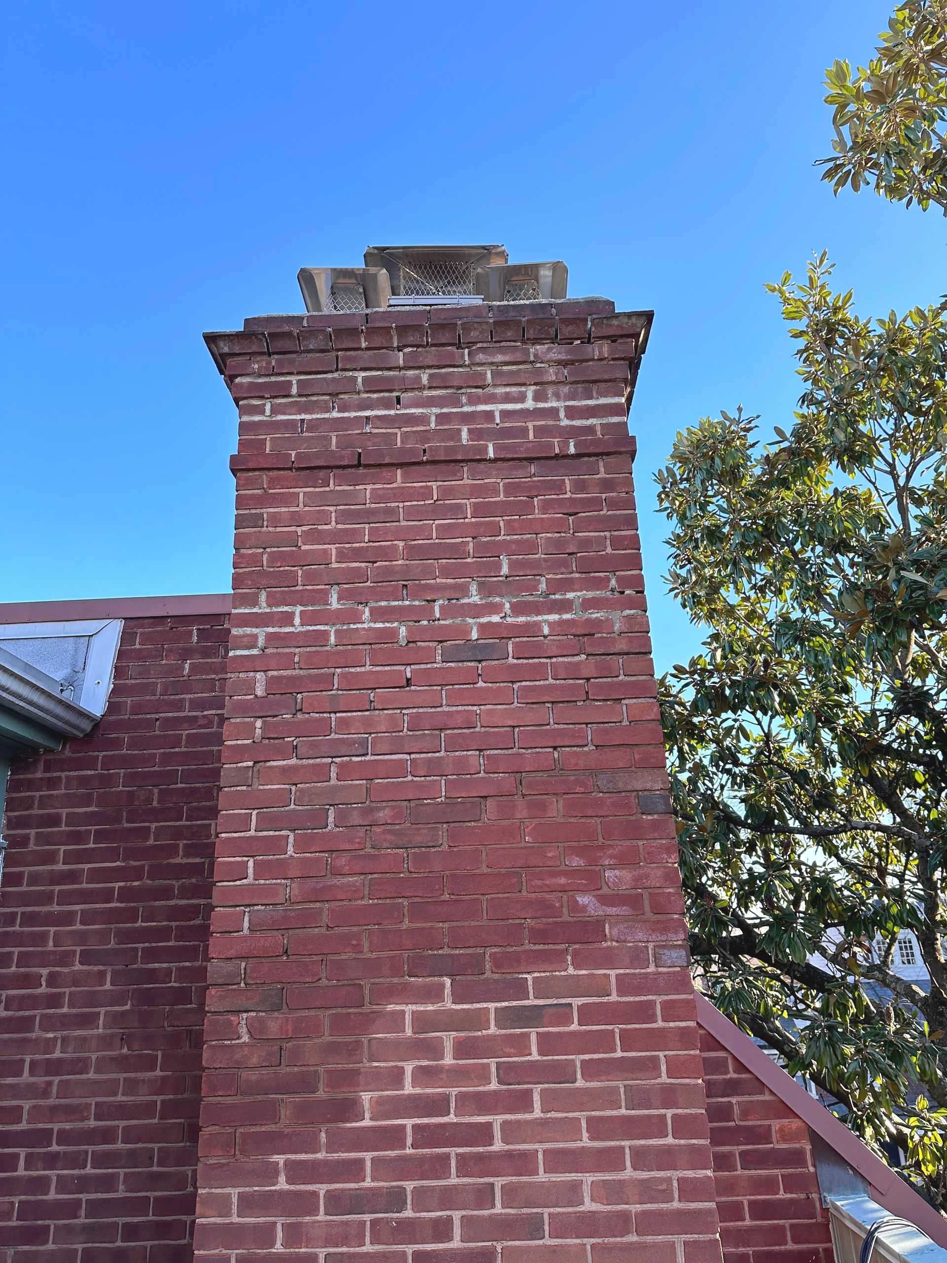 A red brick chimney on top of a brick building