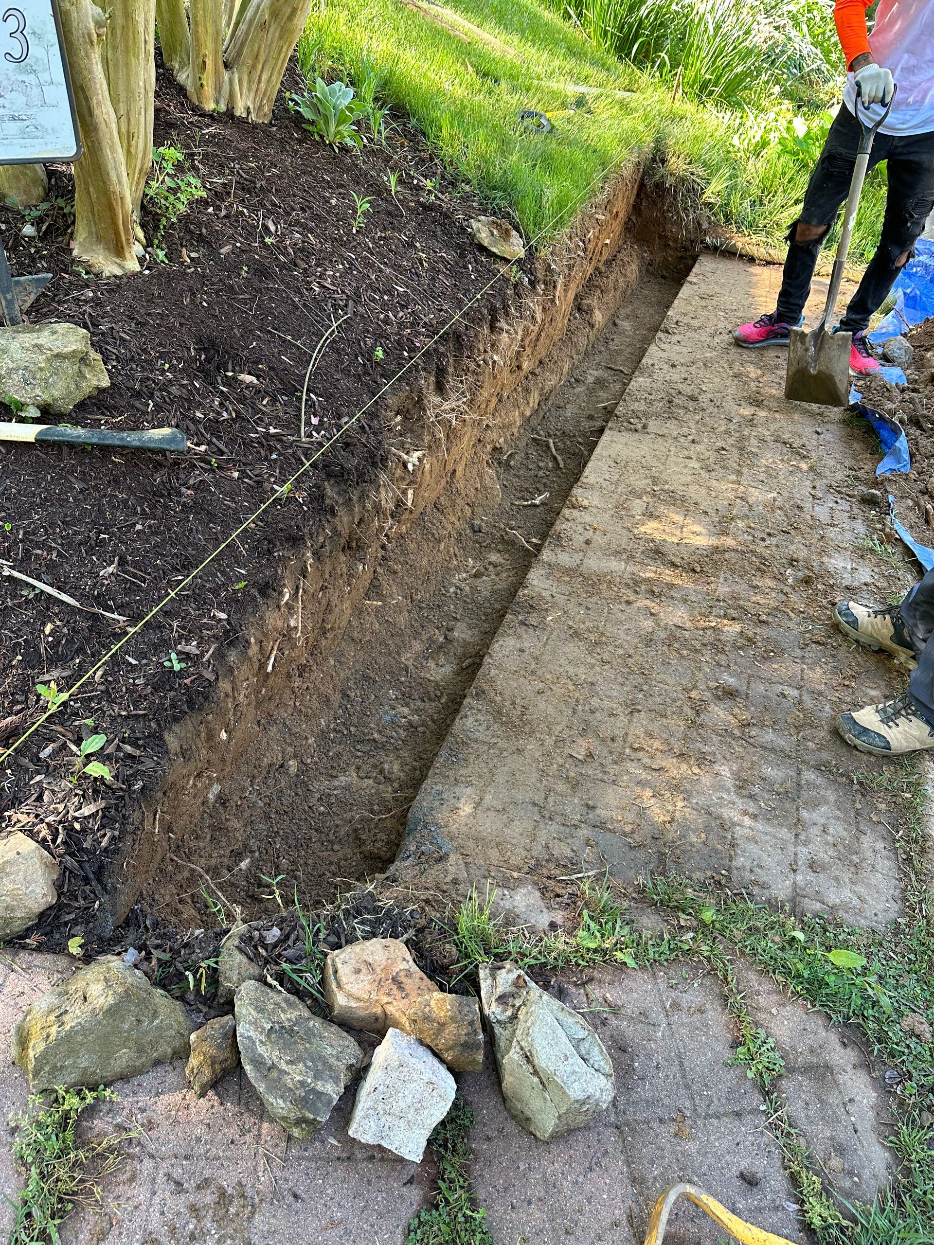 A group of people are preparing ground to install a  retaining wall.