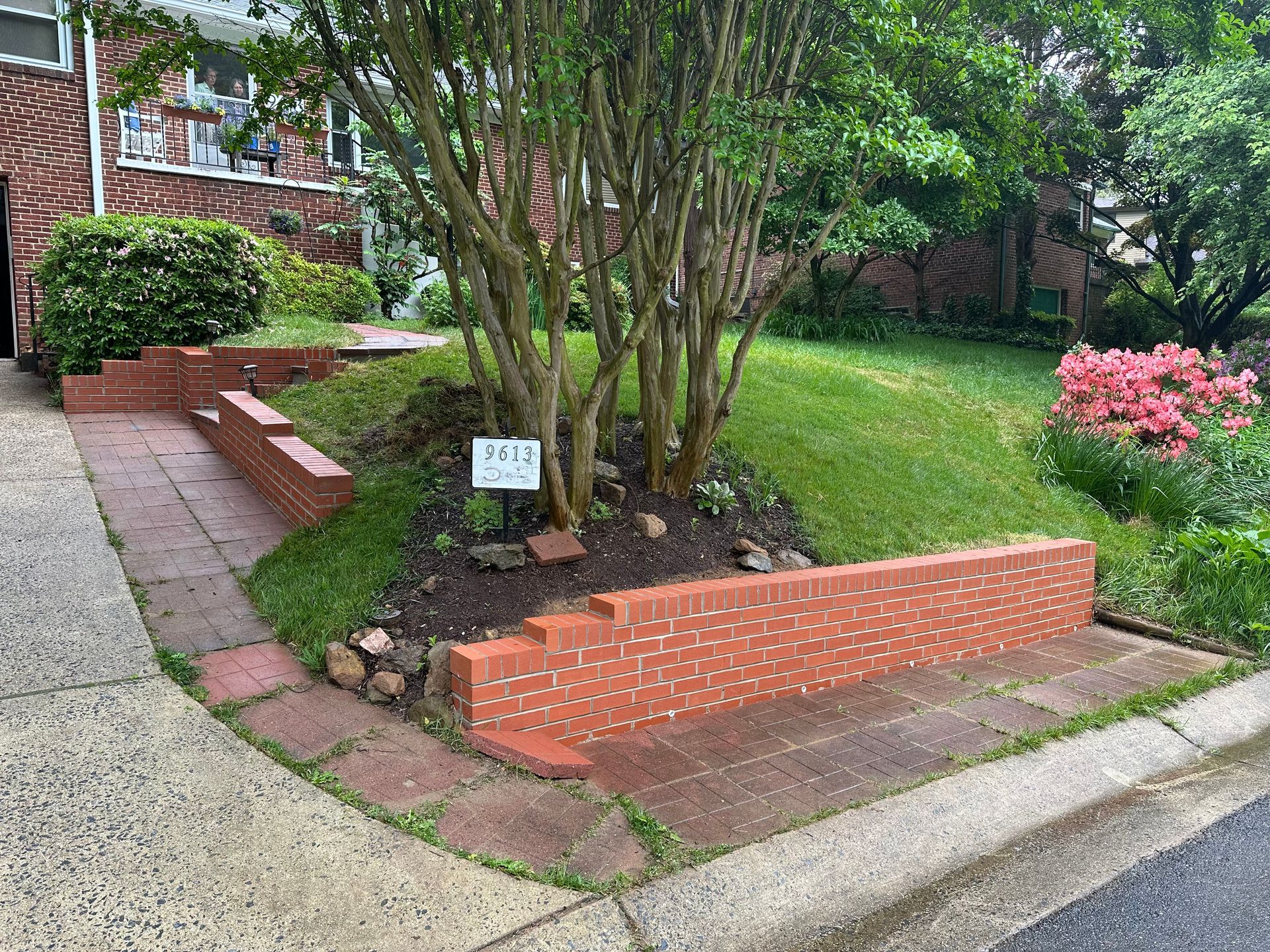 There is a brick retaining wall near a sidewalk and walkway.