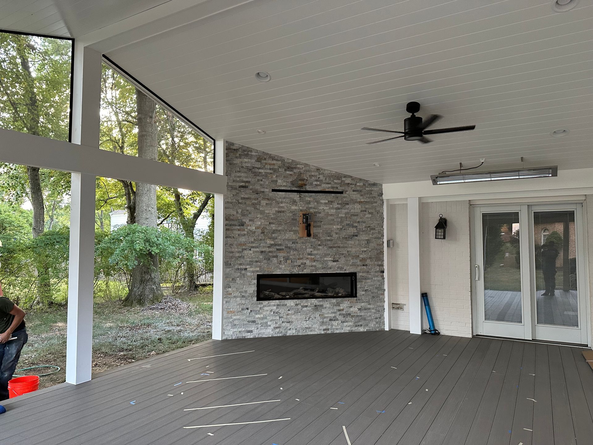 A large enclosed room with a gas fireplace and a ceiling fan.