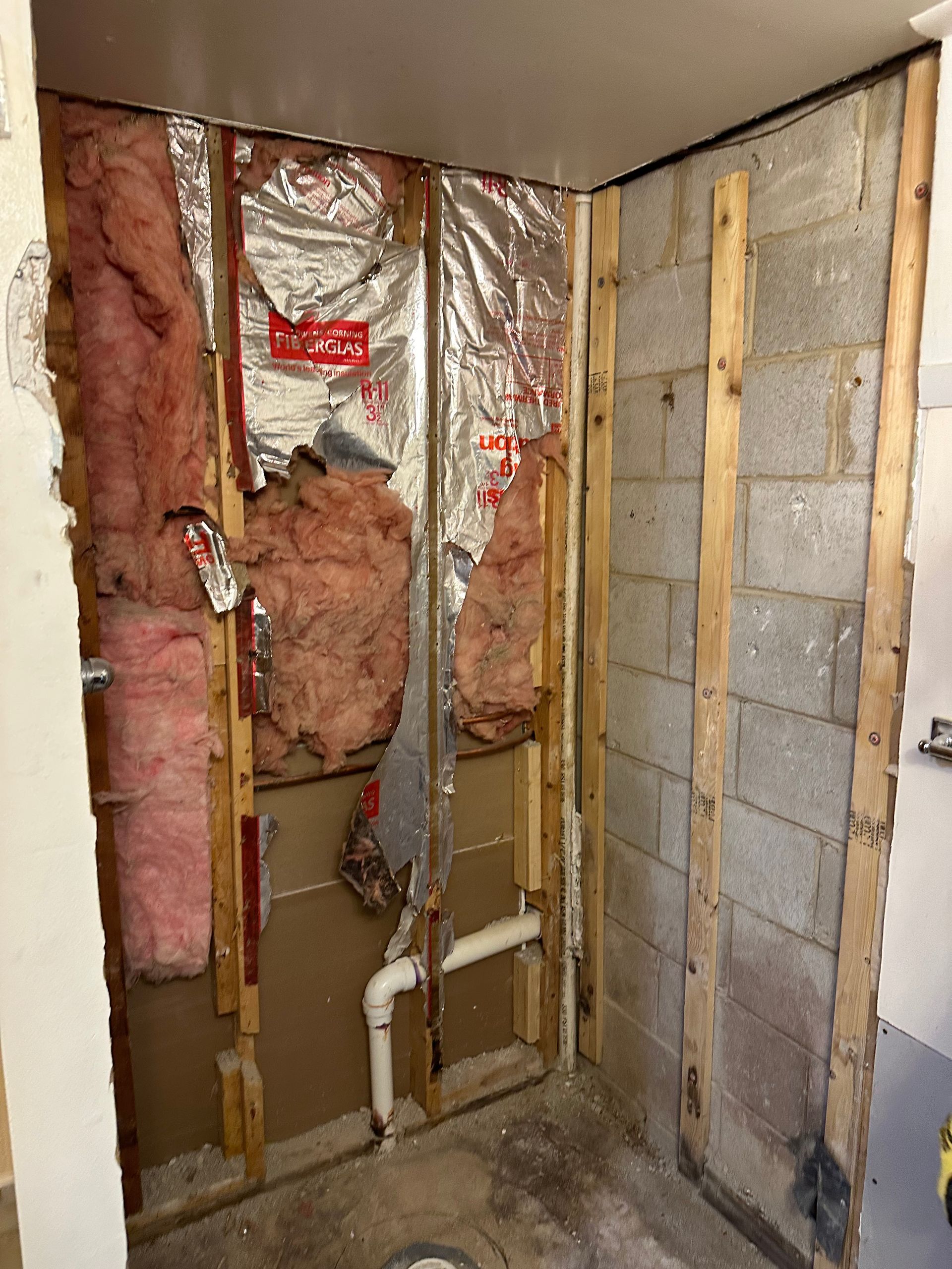 A bathroom shower showing insulation and plumbing.