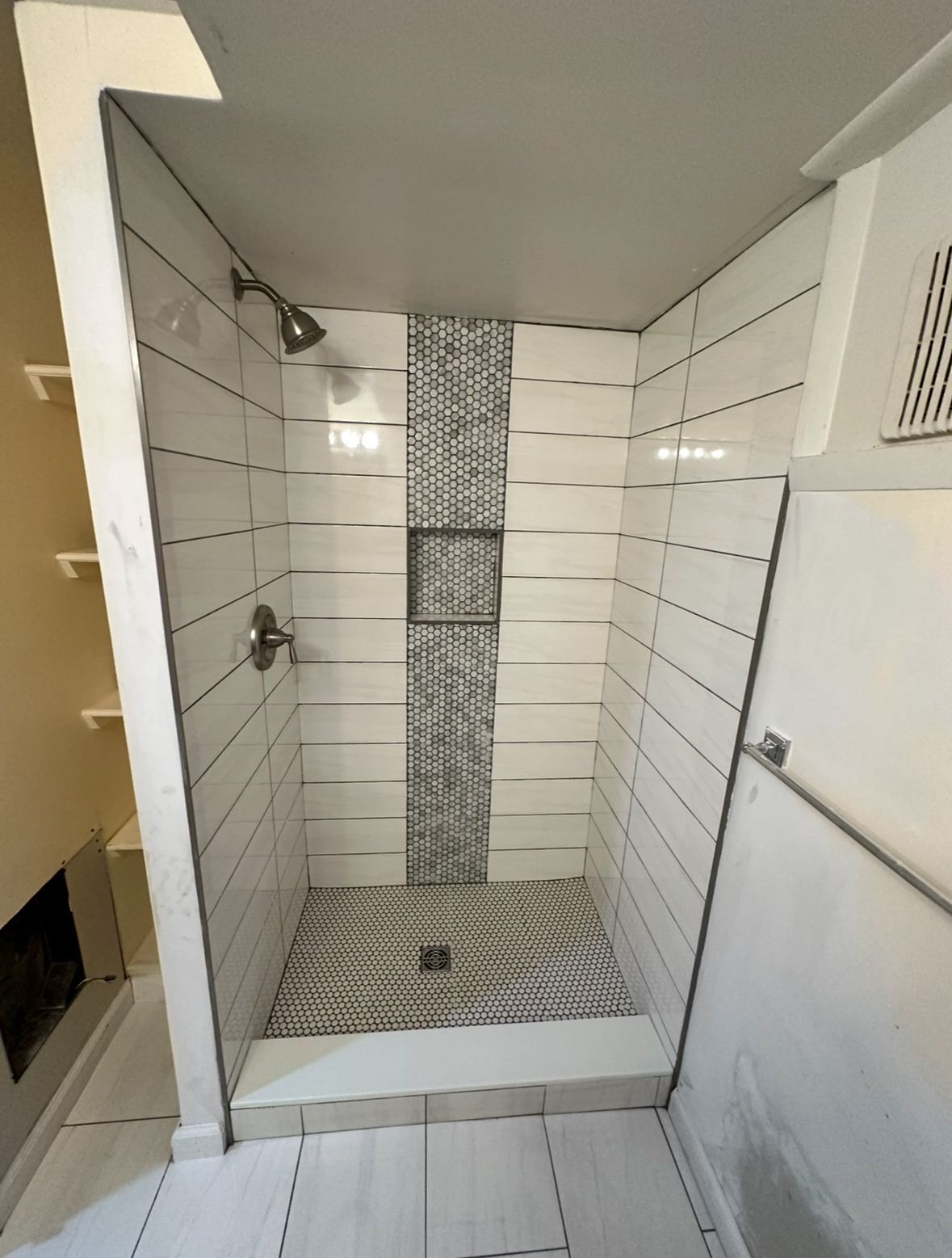A bathroom with white tiles and a walk in shower