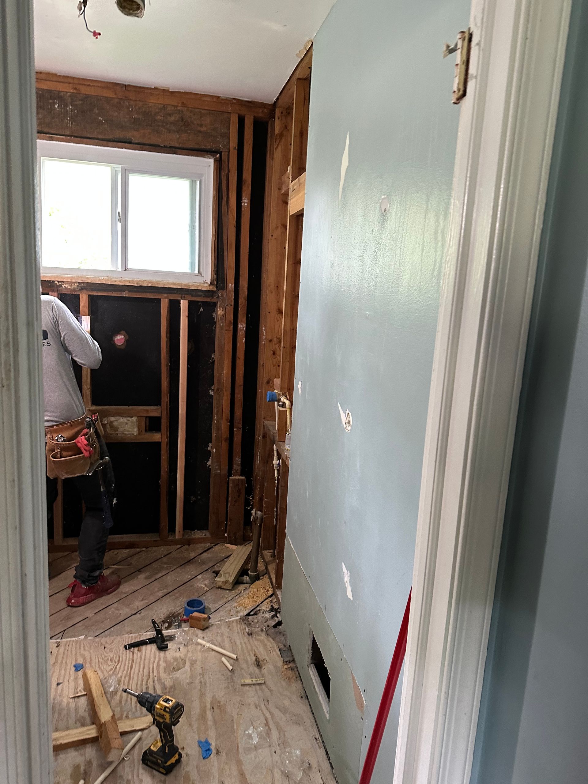 A man is working on a bathroom in a house.