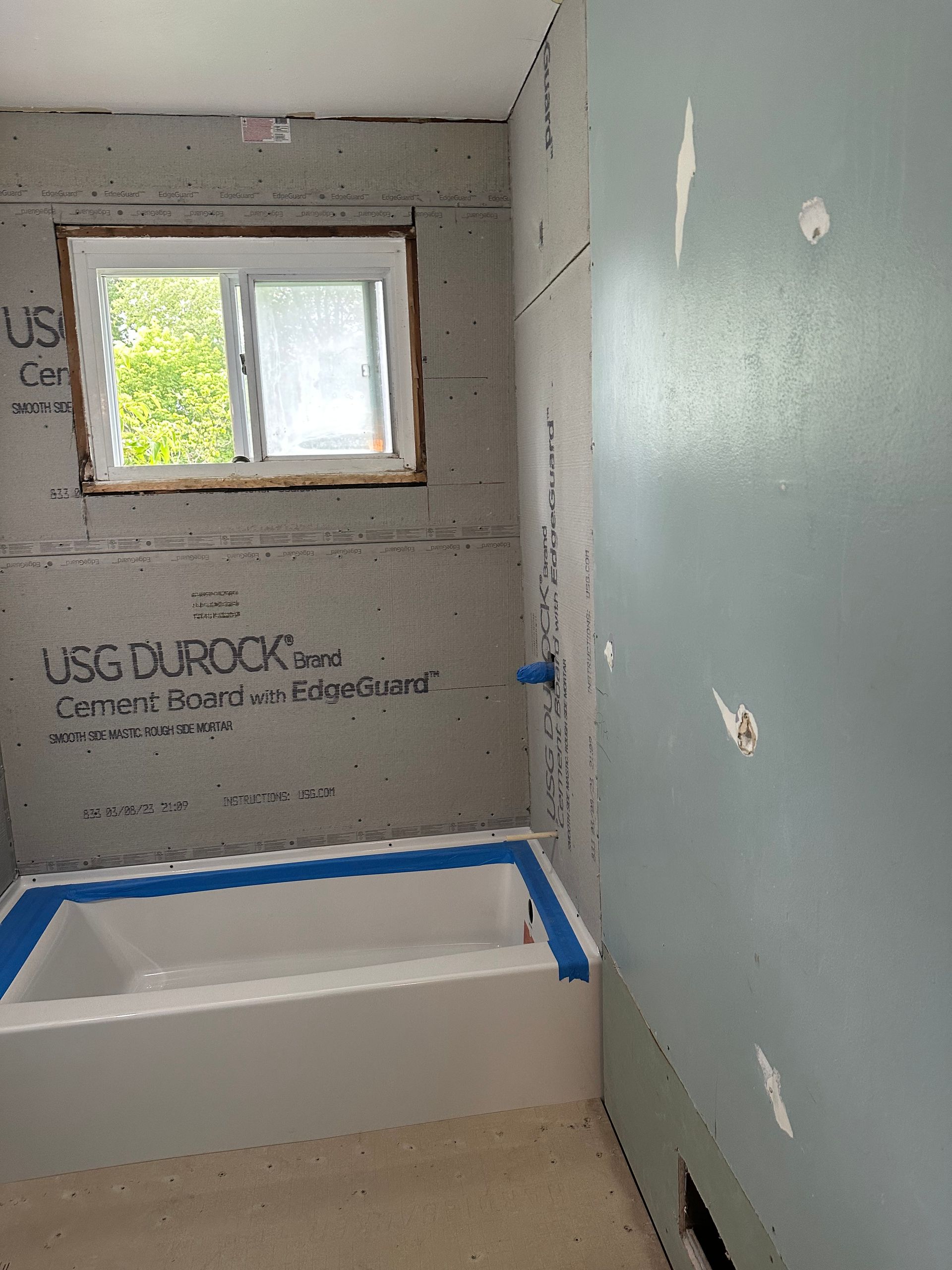 A bathroom under construction with a tub and a window.