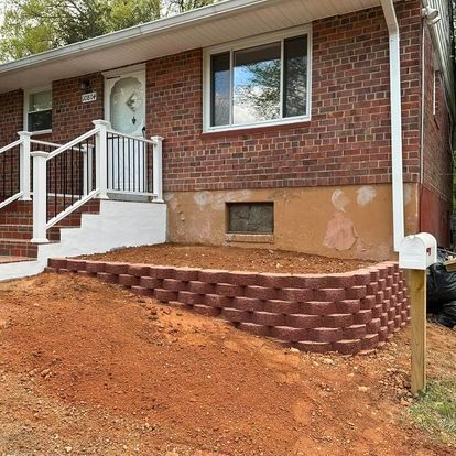A brick house with stairs and a retaining wall in front of it.