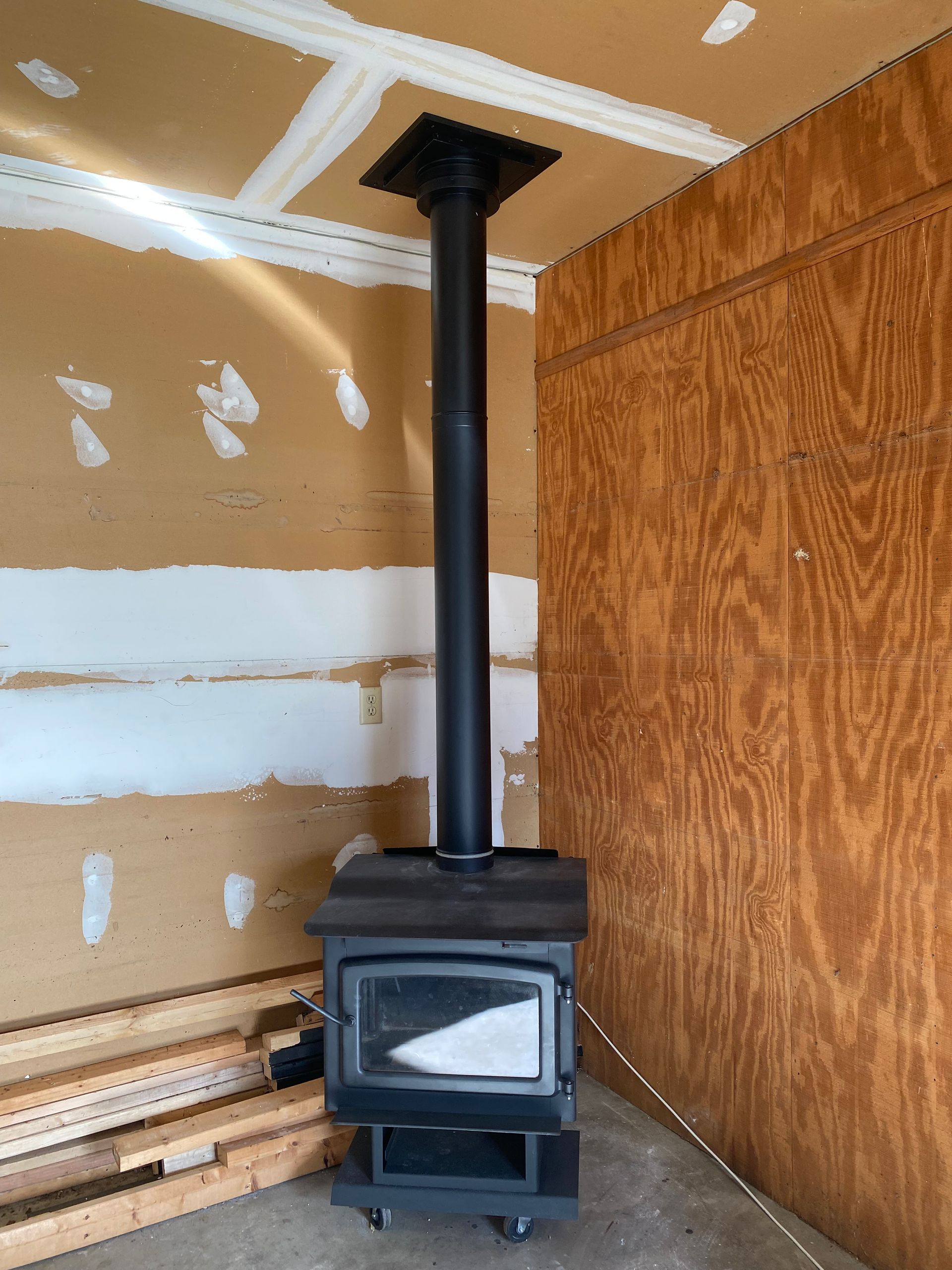 A wood stove is sitting in a room with a wooden wall.