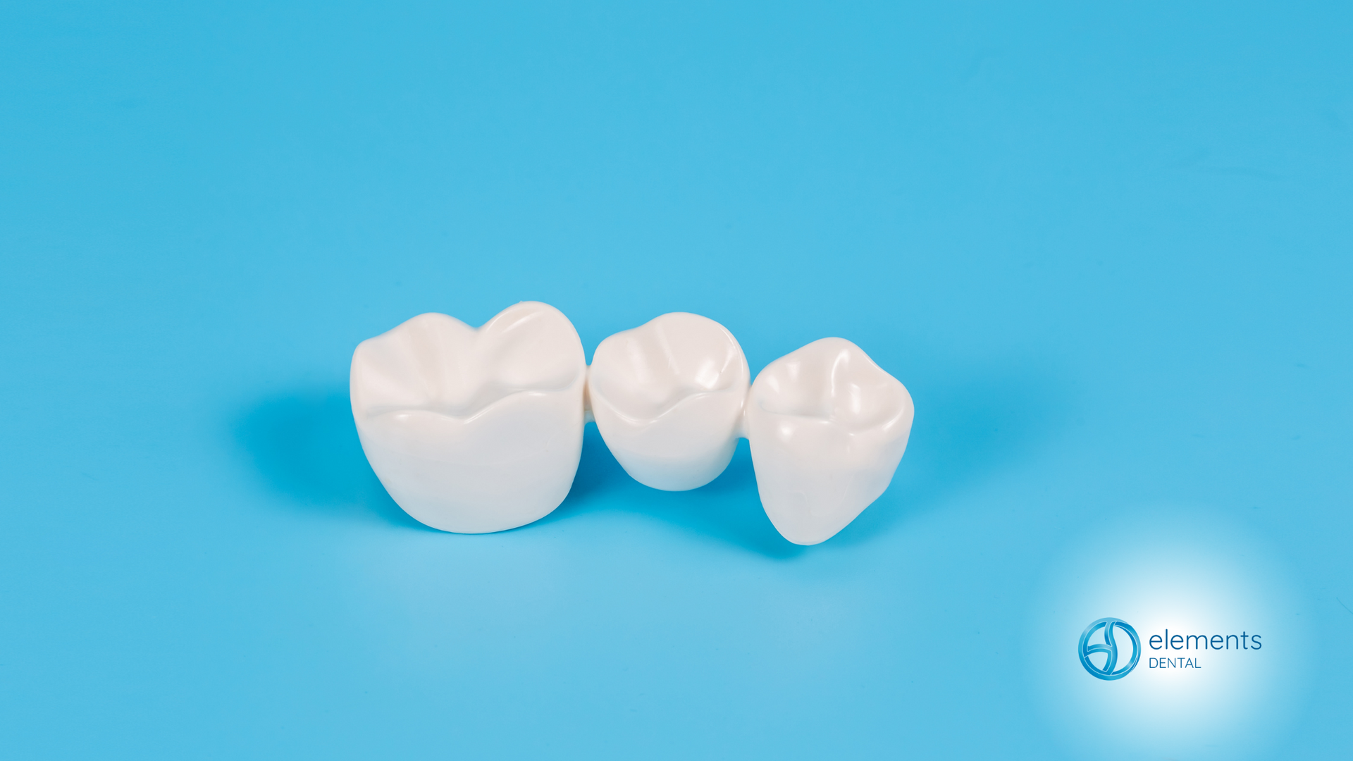 Three white teeth are sitting on a blue surface.