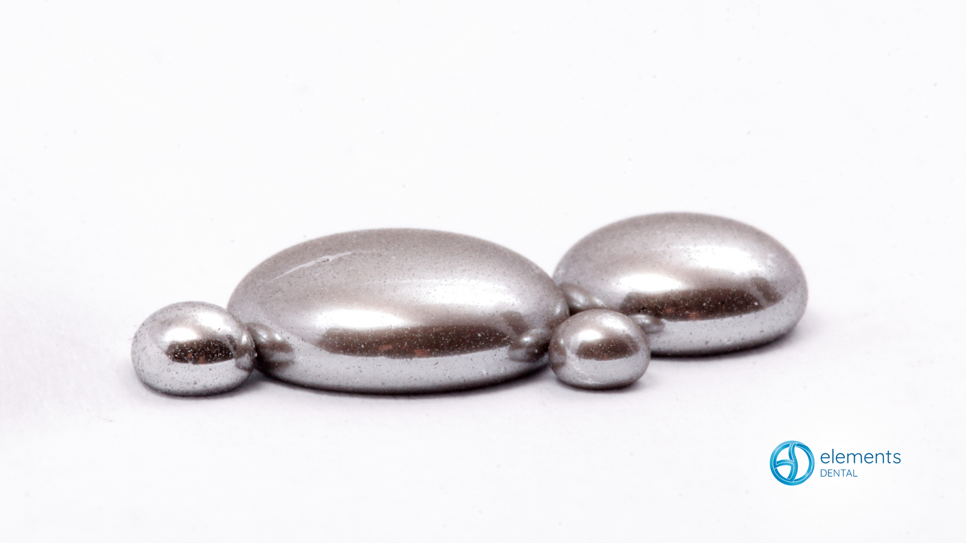 Three silver balls are sitting on top of each other on a white surface.