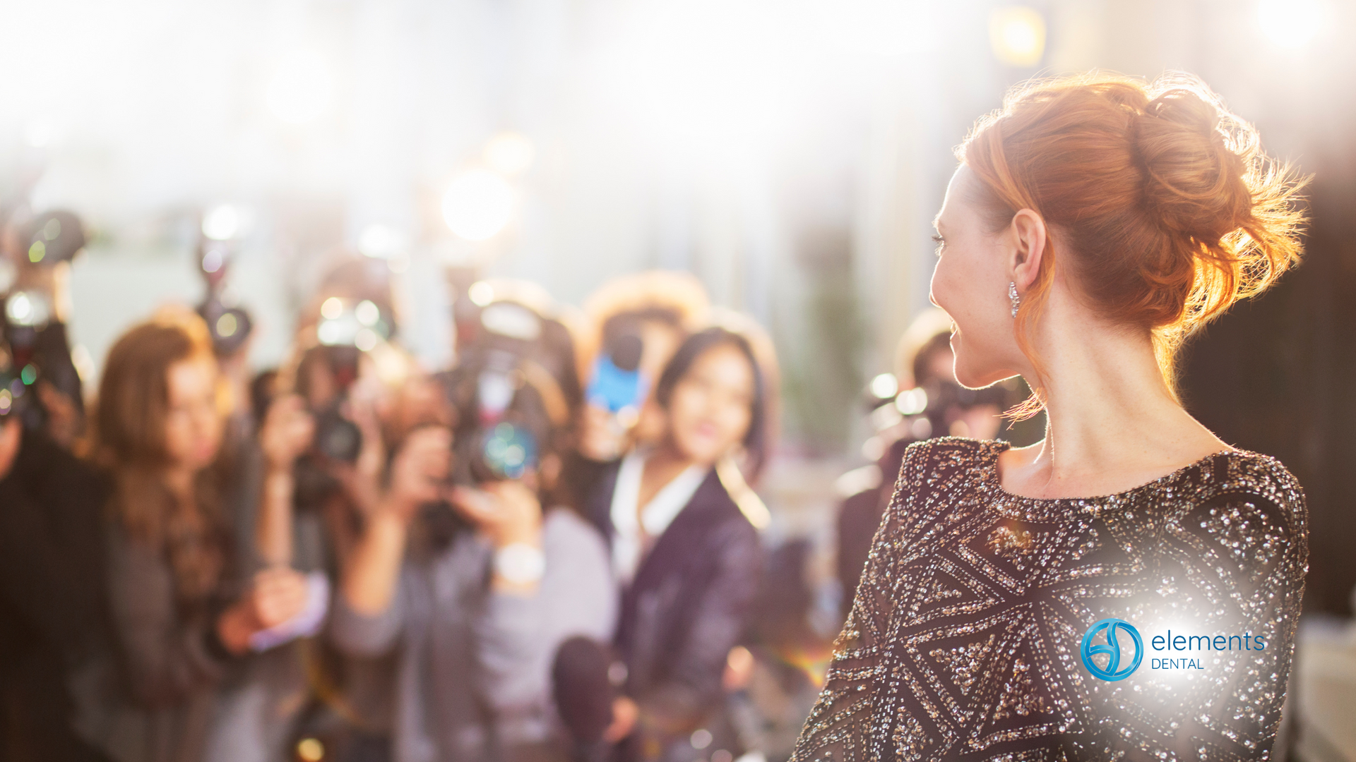 A woman is standing in front of a crowd of people taking pictures of her.