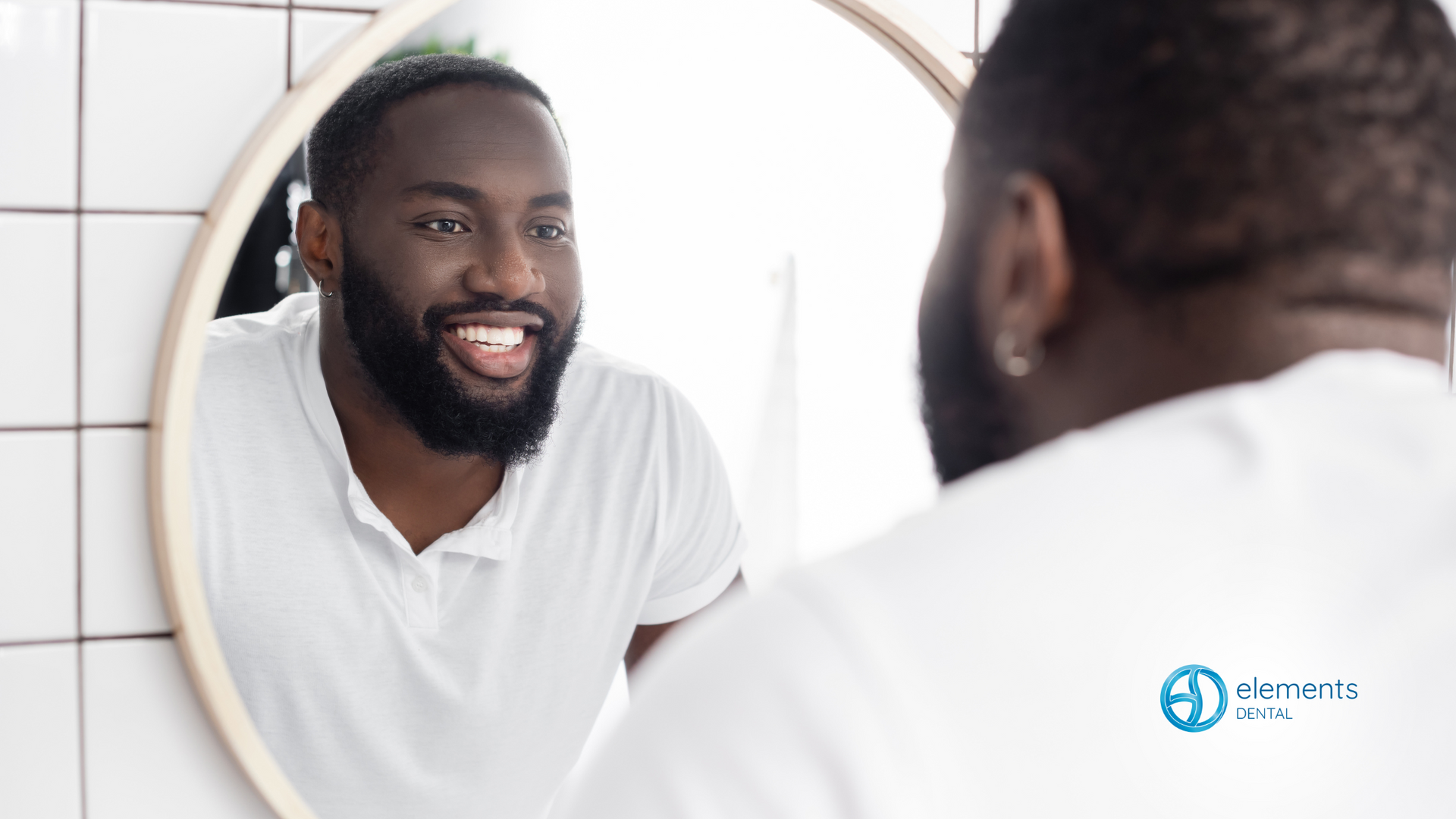 A man is smiling at himself in a bathroom mirror.
