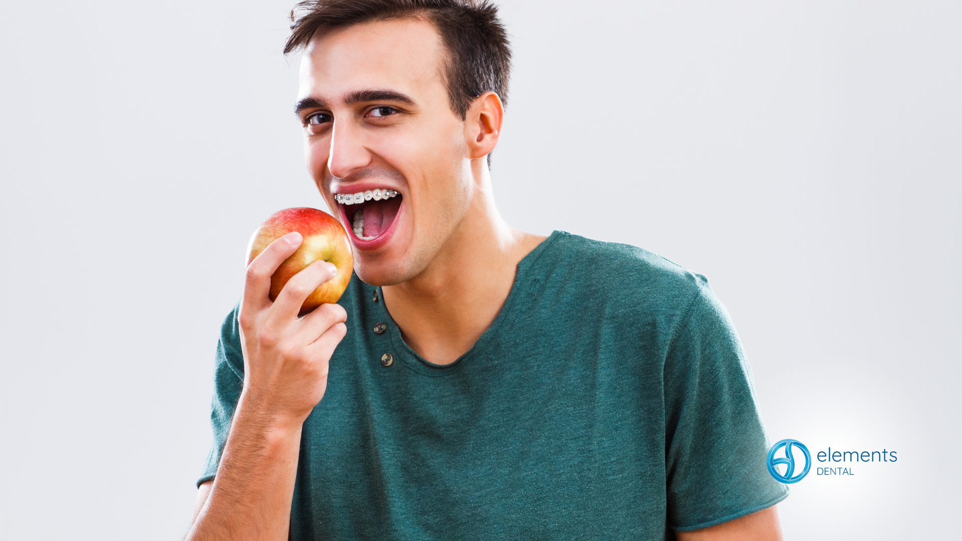 A man with braces on his teeth is eating an apple.