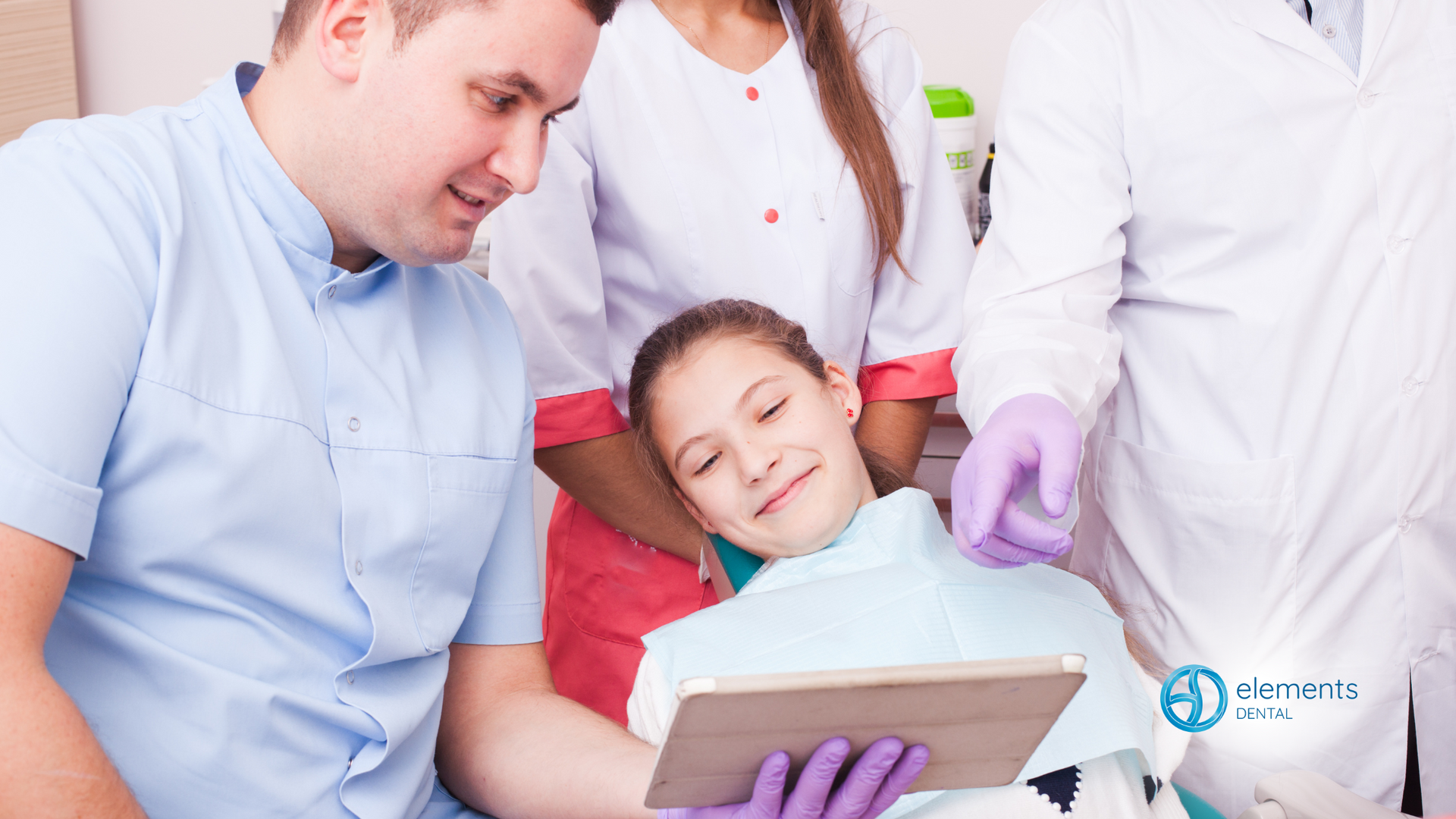 A dentist is teaching a young girl how to use a tablet.