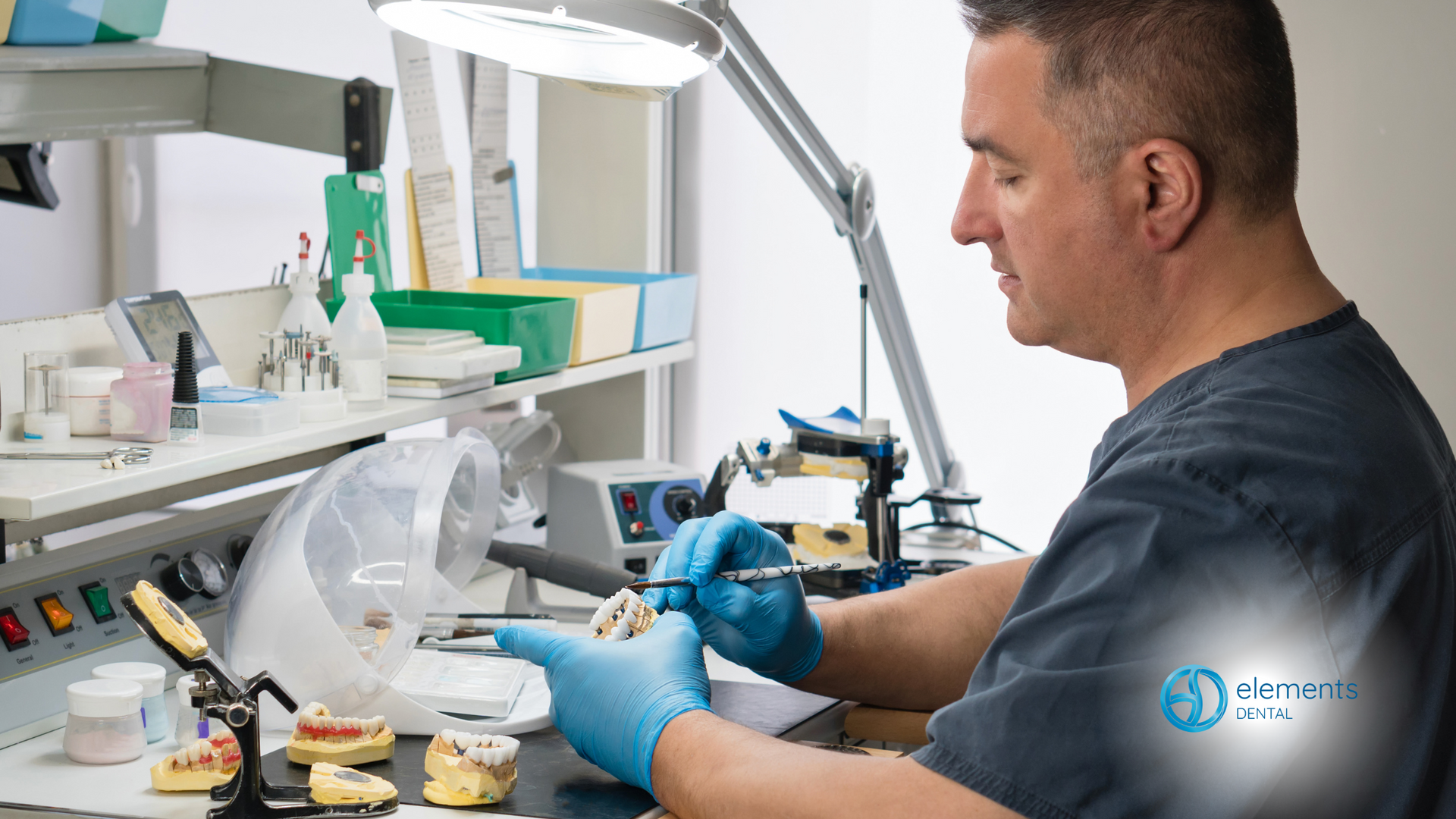 A dentist is working on a denture in a lab.
