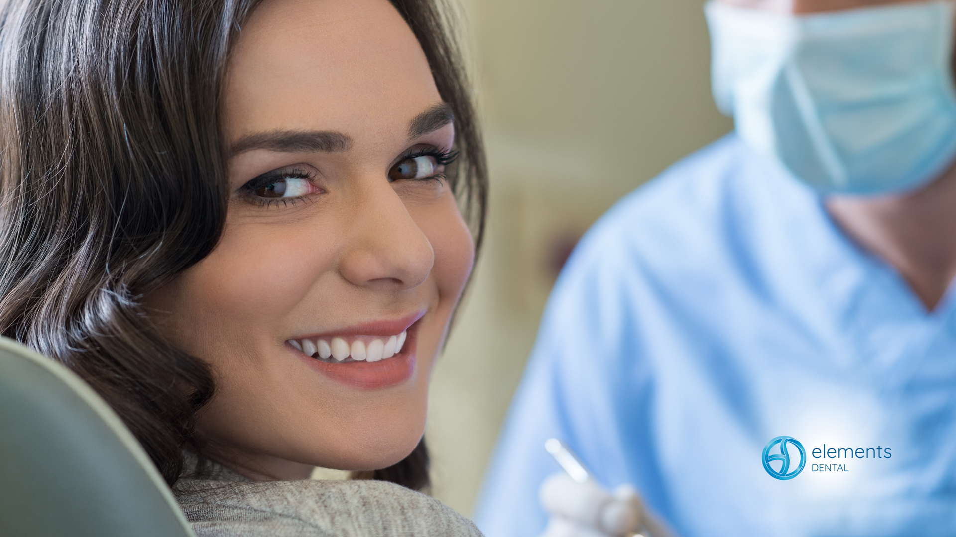A woman is smiling while sitting in a dental chair.