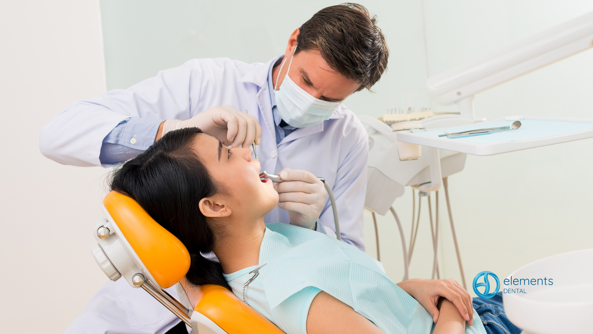 A woman is sitting in a dental chair while a dentist examines her teeth.