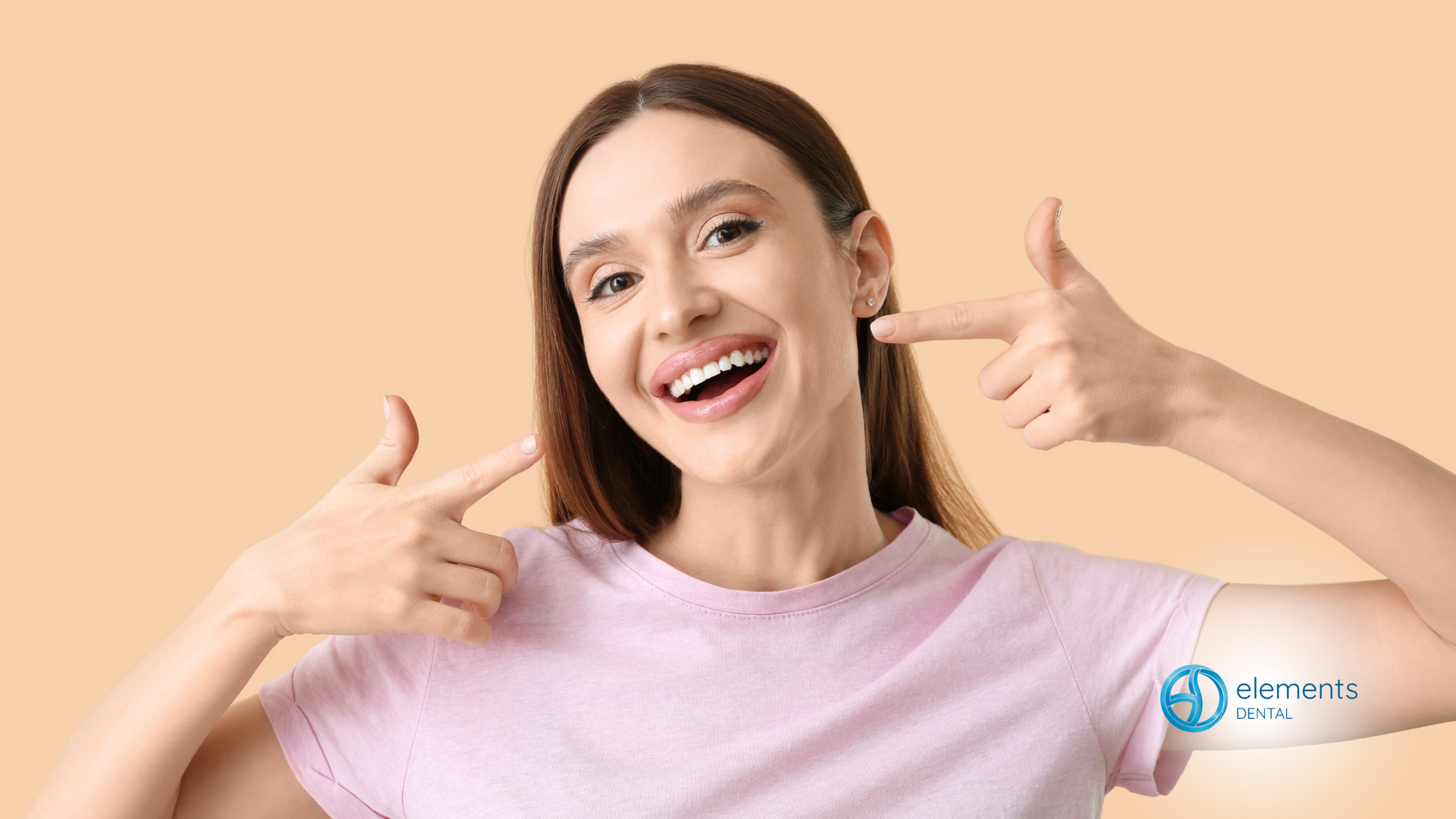 A woman is smiling and pointing at her teeth.