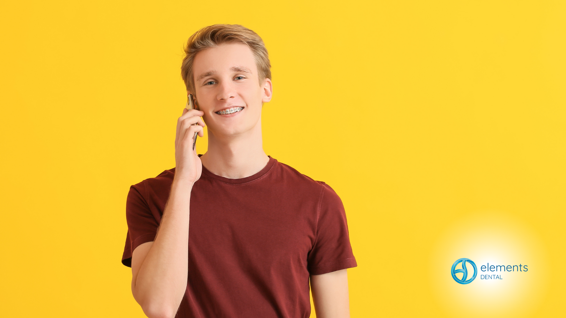 A young man is smiling while talking on a cell phone.