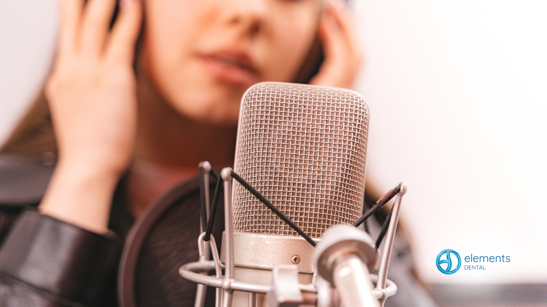 A woman is singing into a microphone while wearing headphones.