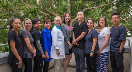 Group of people standing outdoors on a garden path, smiling at the camera.