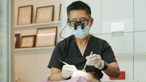 Hand pulling a loose front tooth from a person's mouth, with visible bleeding around the gum.