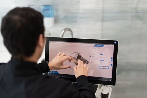 Dentist holding dental implant model beside smiling woman in clinic