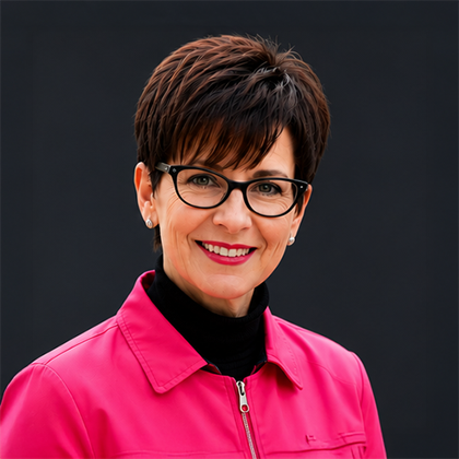 Portrait of a smiling person in glasses and a bright pink jacket on a dark background