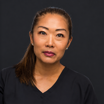 Portrait of a woman with dark hair in a black top against a dark background
