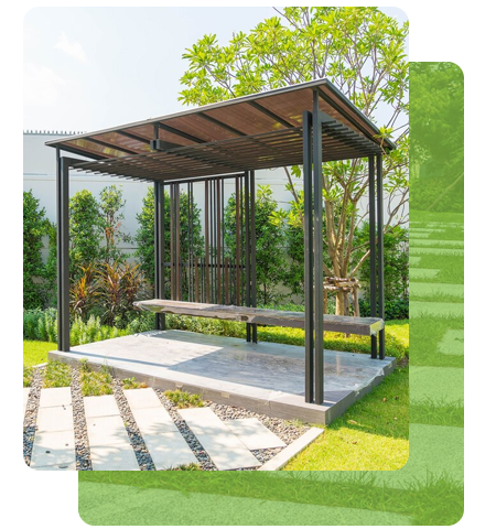 Gazebo avec un banc sur une dalle de béton, entouré de verdure et d'un chemin de dalles.