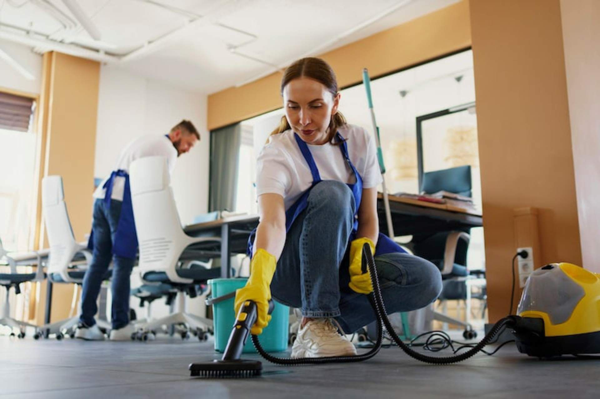 Cleaning professionals use a vacuum and supplies to clean the floors of a modern office space.