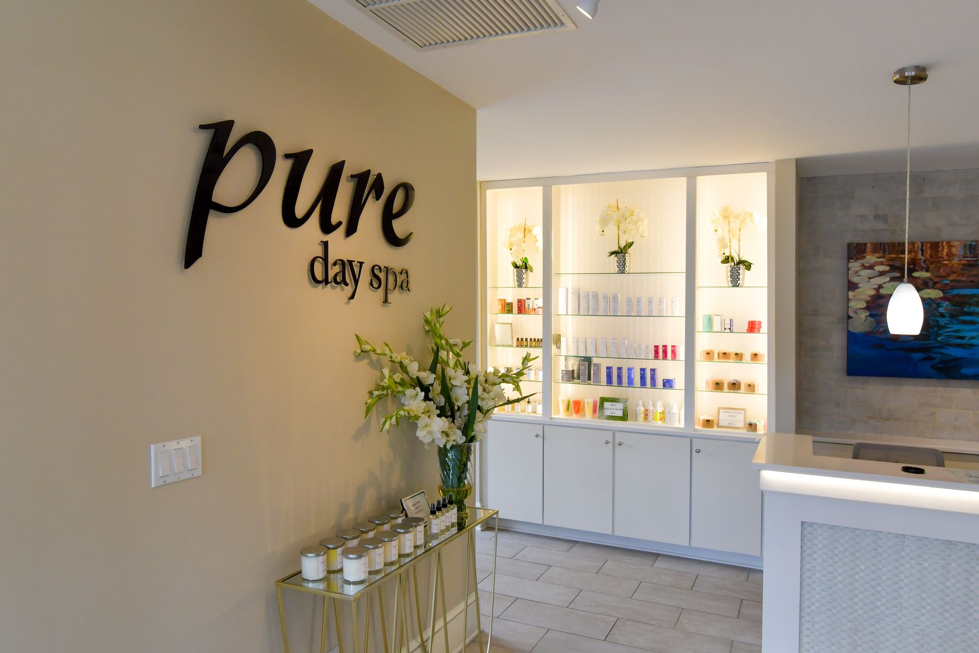 Pure Day Spa reception with white shelves, flowers, and a light beige lobby