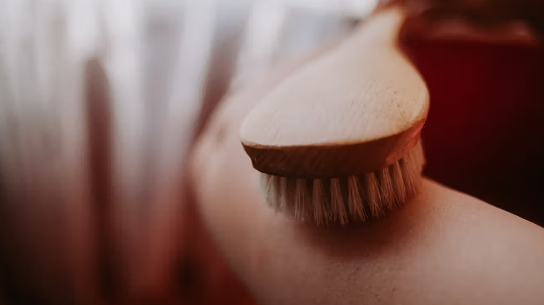 A person is using a wooden brush on their arm.