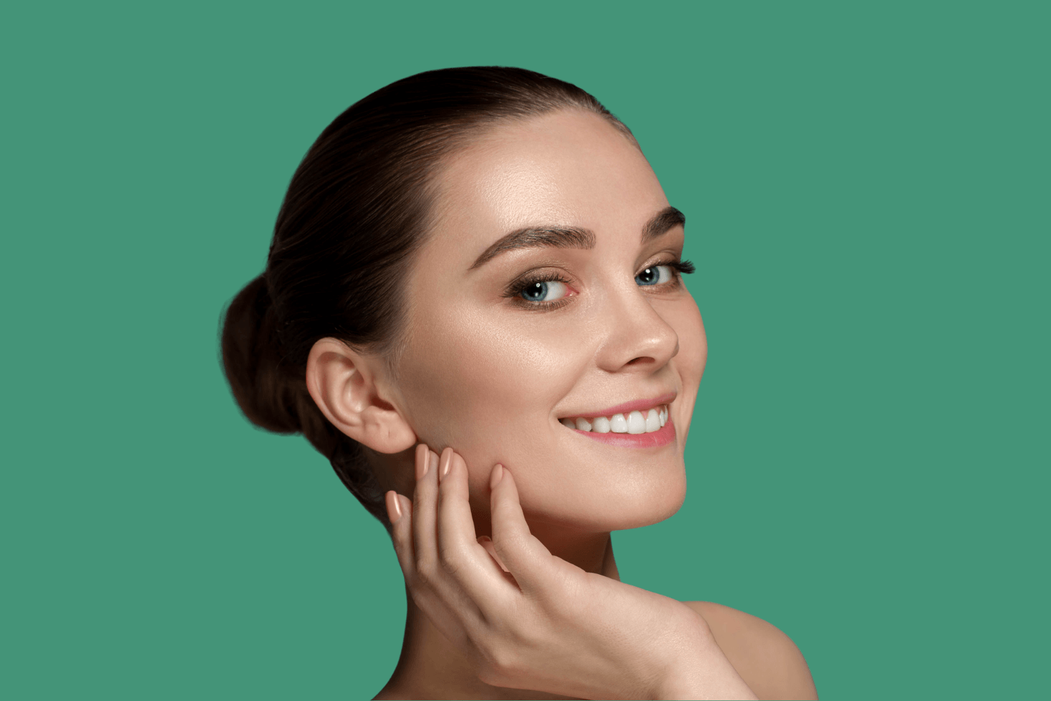 A woman is touching her face with her hand and smiling.