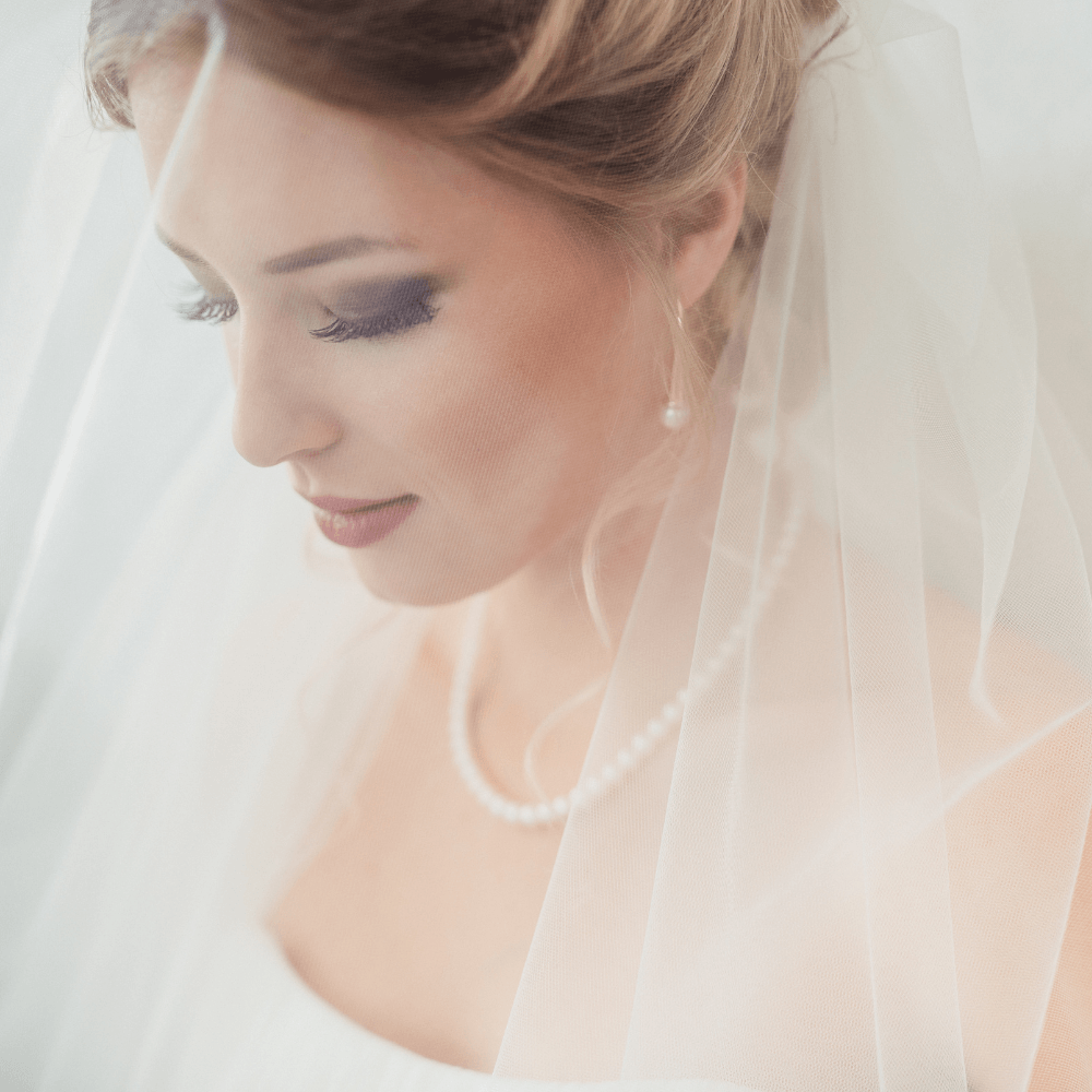 A close up of a bride wearing a veil and pearls.