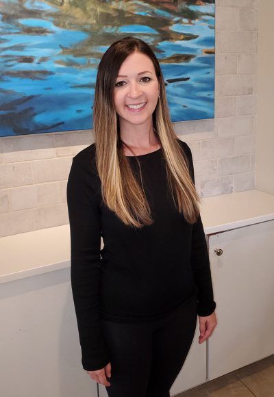 A woman in a black shirt is standing in front of a painting.