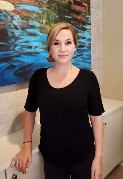 A woman in a black shirt is standing in front of a painting