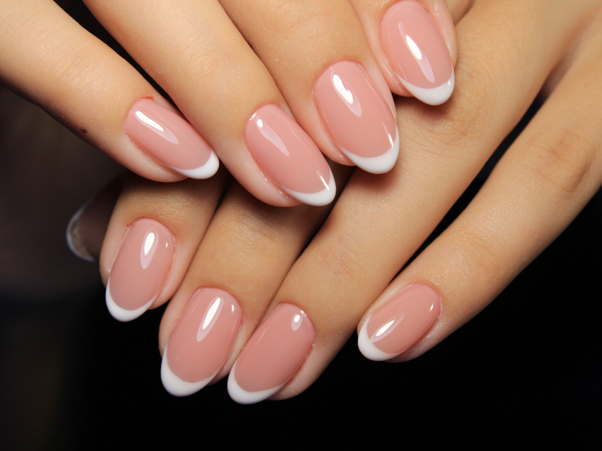 A close up of a woman 's nails with a french manicure A close up of a woman 's nails with a french manicure