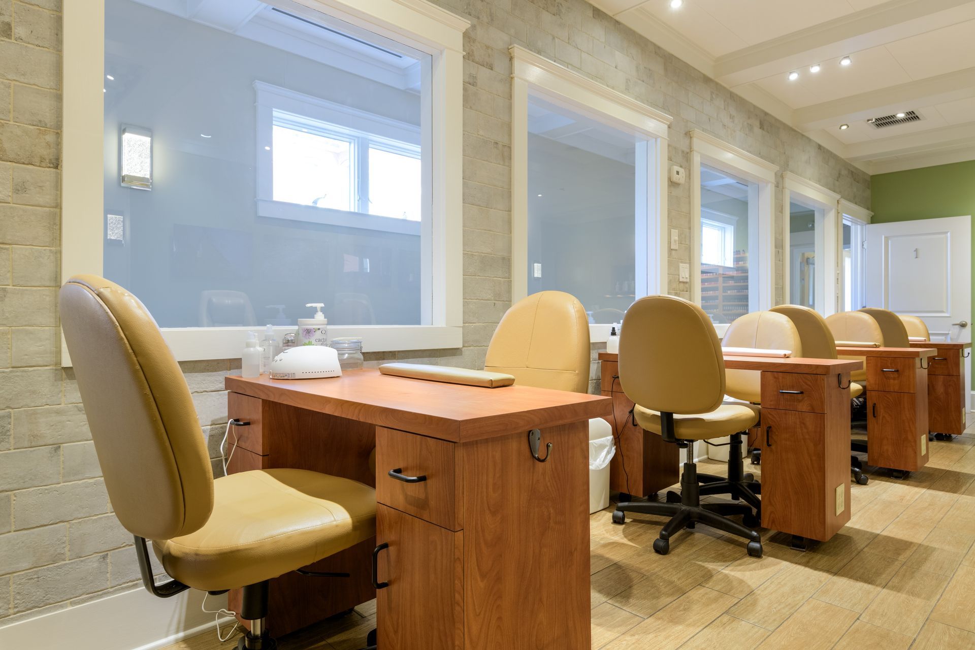 A row of wooden tables and chairs in a nail salon.