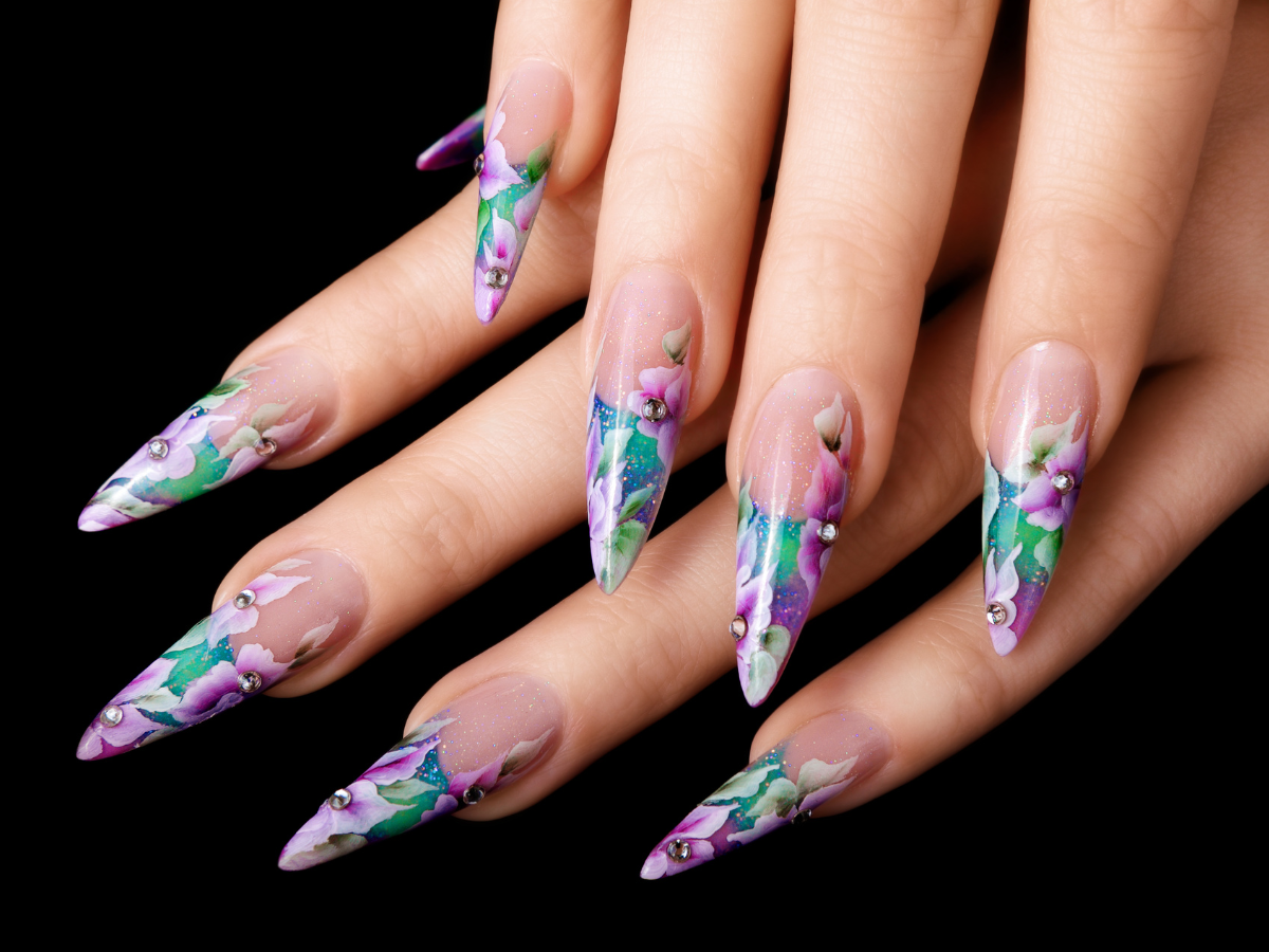 A close up of a woman 's nails with a floral design A close up of a woman 's nails with a floral design