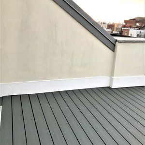 Rooftop terrace with gray deck boards and cream-colored walls under a sloped roof edge