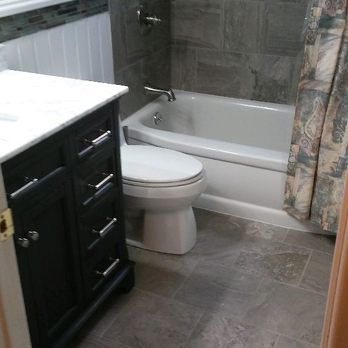 Bathroom with black vanity, white toilet, and tub with gray tile walls and floral shower curtain